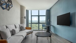 Una sala de estar moderna con un sofá, una mesita redonda y un televisor montado en la pared.