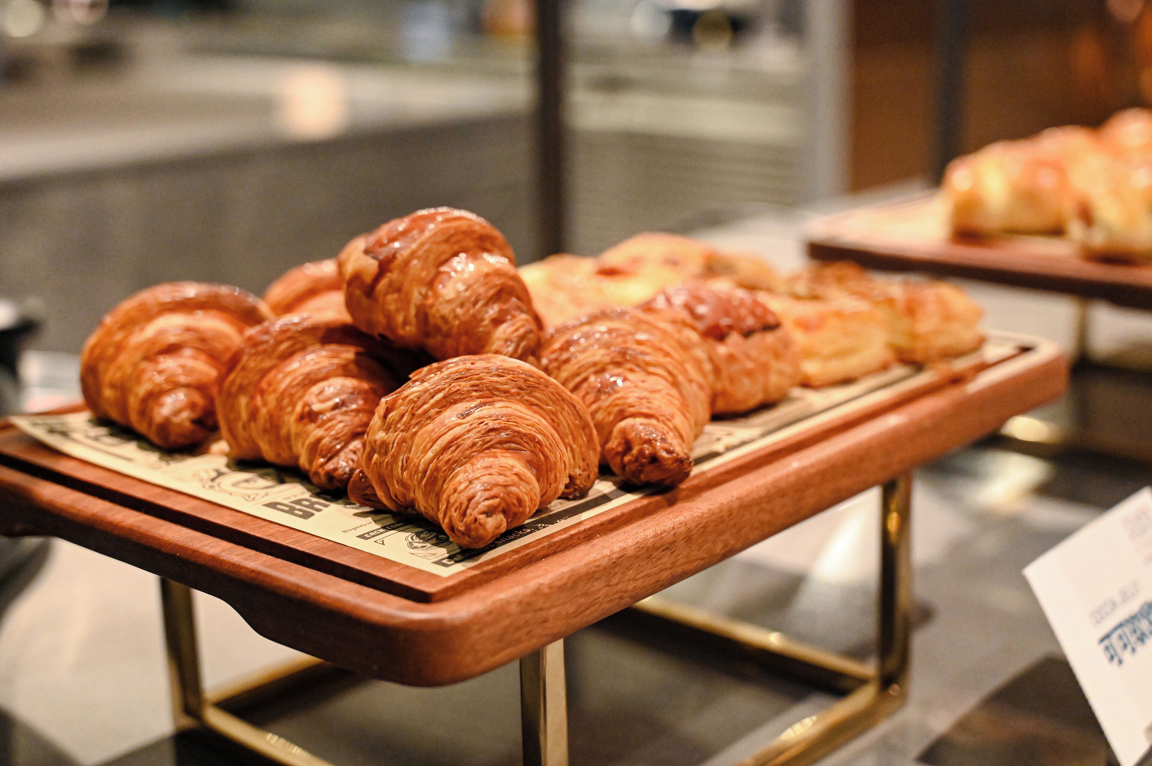 A display of croissants on a wooden stand with a metal frame.