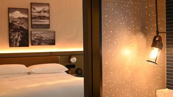 Una habitación de hotel con una cama, una mesita de noche y obras de arte colgadas en la pared.