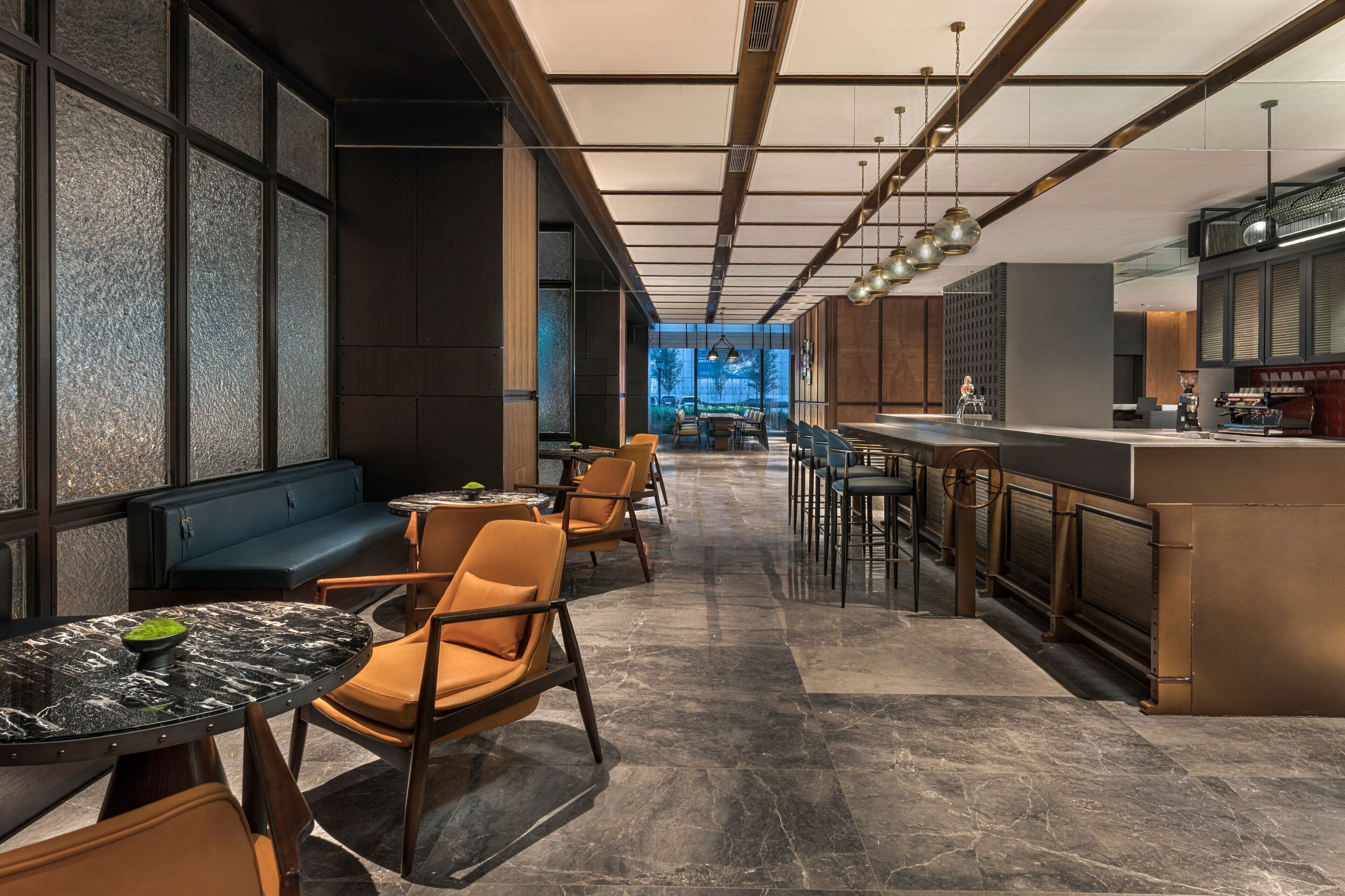 A modern restaurant with a bar area, seating along the walls, and a view of the outdoors.