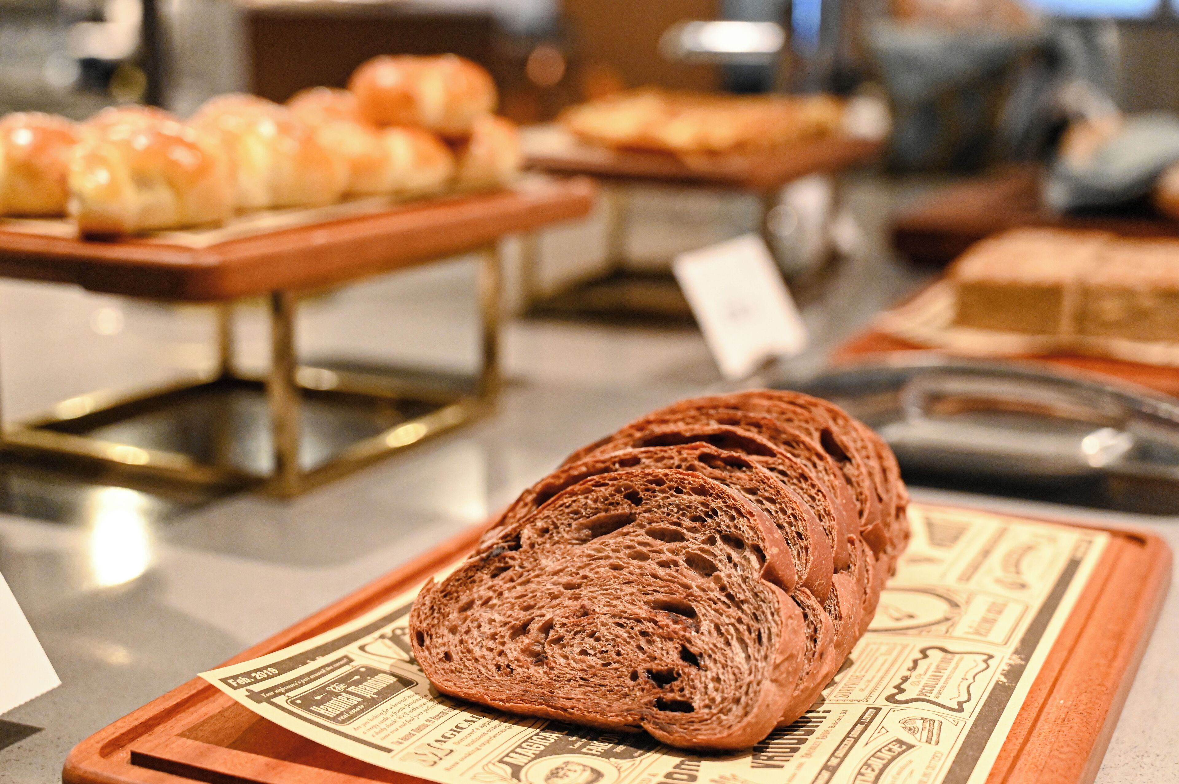A display of various breads and pastries on trays in a bakery setting.