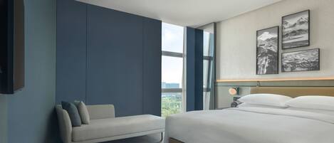 A modern hotel room with a large bed, a sofa, and a view of the outdoors.
