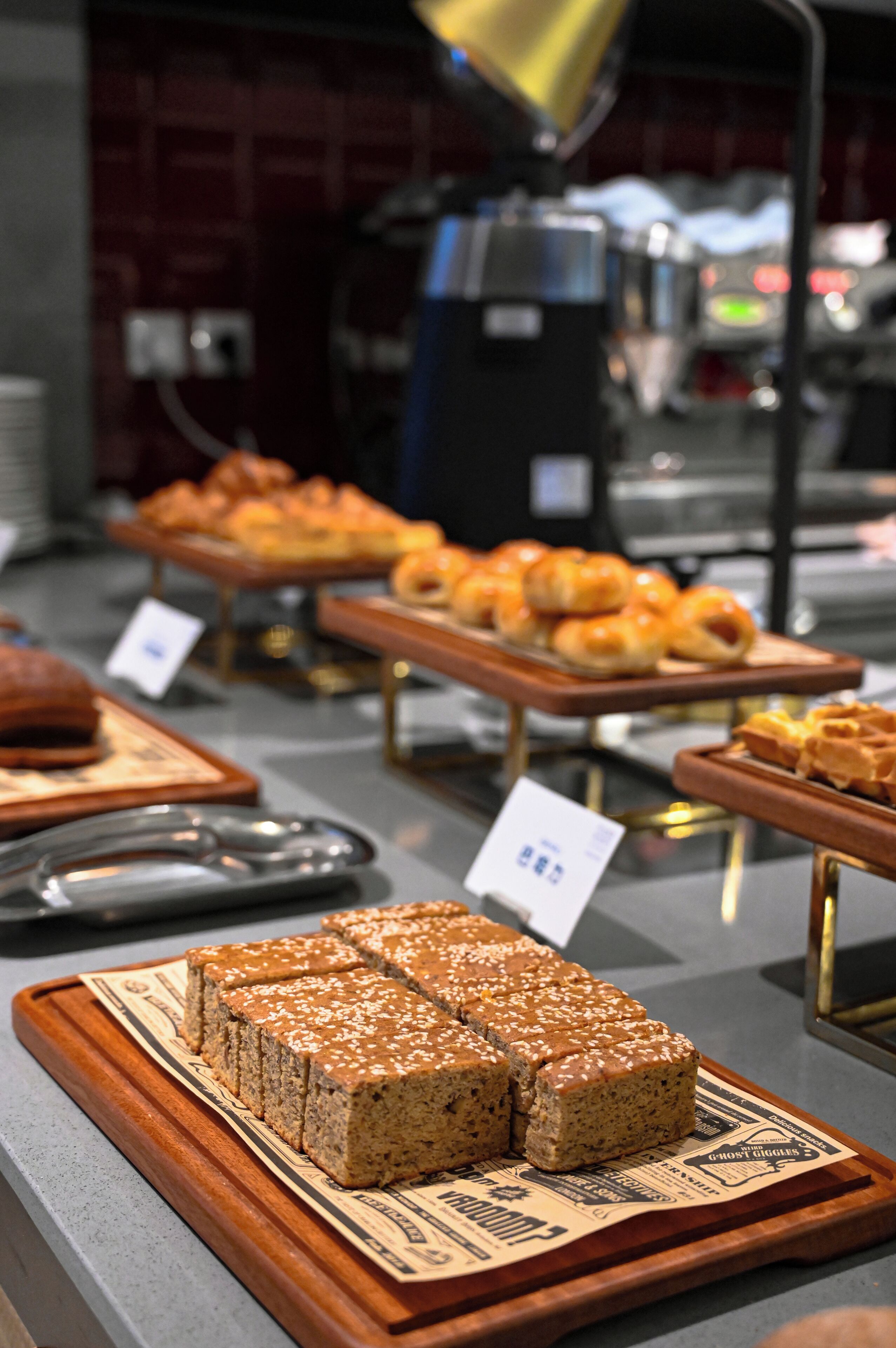 A buffet with various baked goods, including bread and pastries, displayed on wooden serving boards.