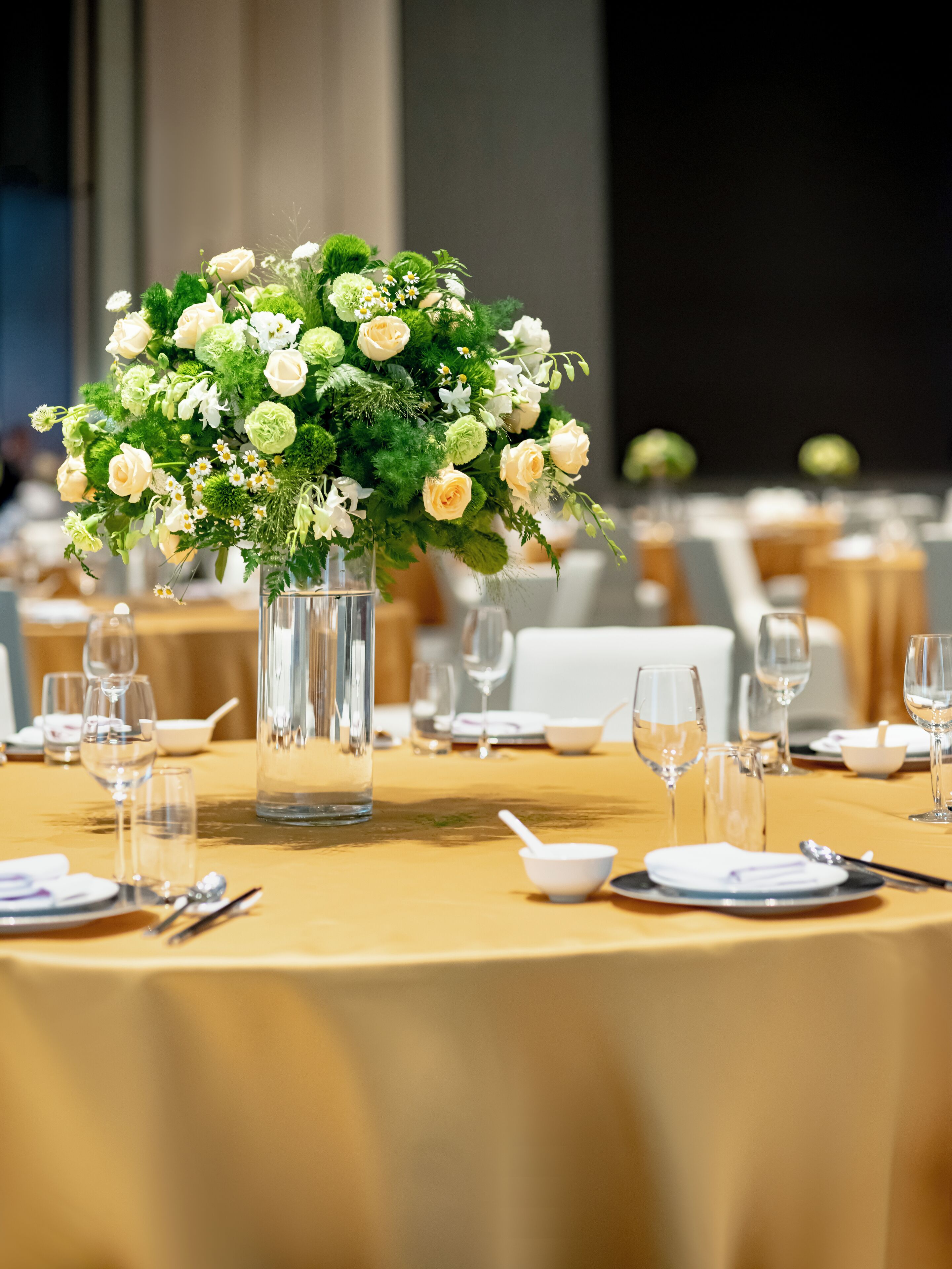 A table set for a formal dining event with a centerpiece of flowers in a clear vase.