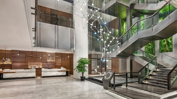 Un vestíbulo moderno con una recepción, una escalera y una planta grande.