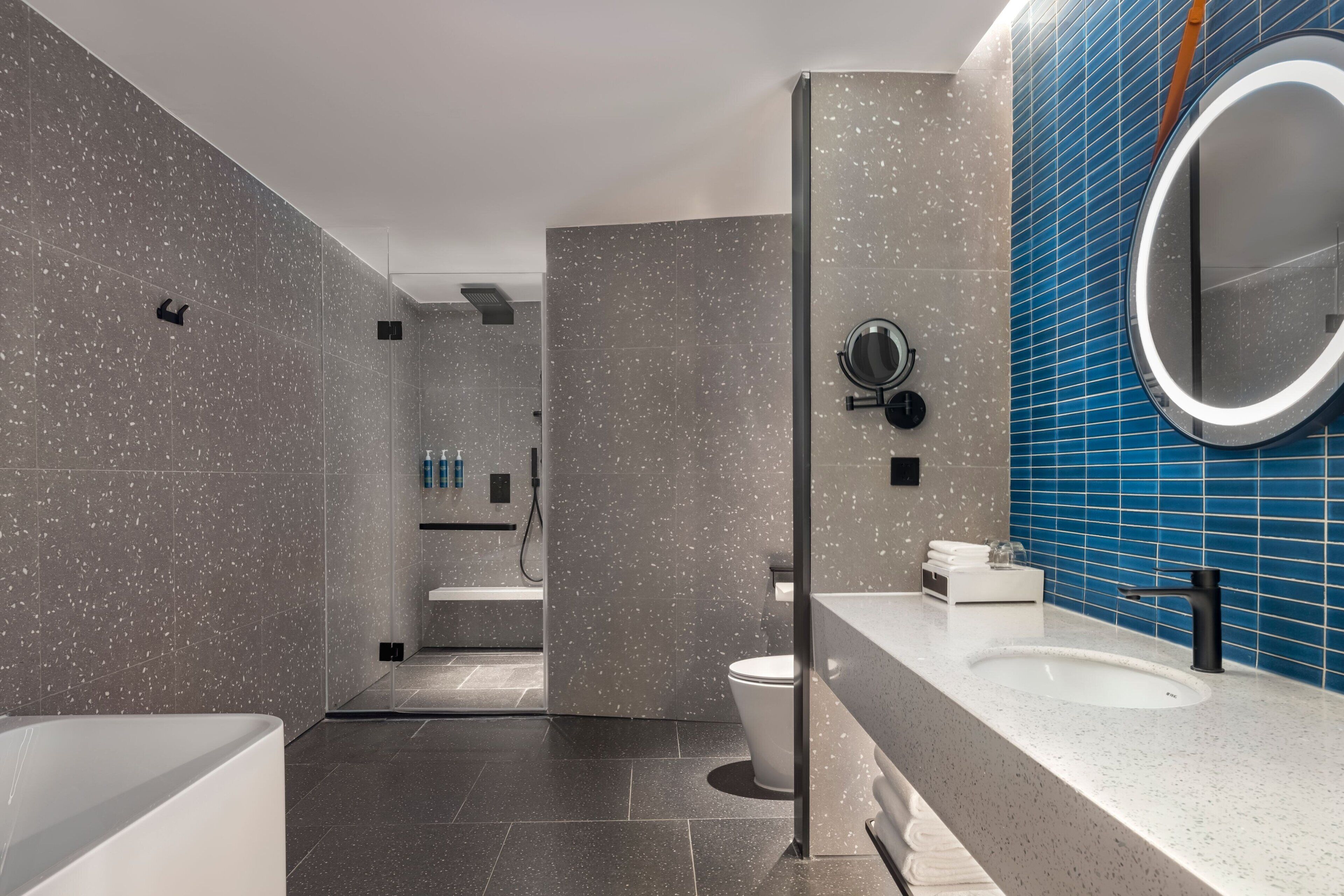Ein modernes Badezimmer mit Badewanne, Waschbecken mit Spiegel und Duschbereich.