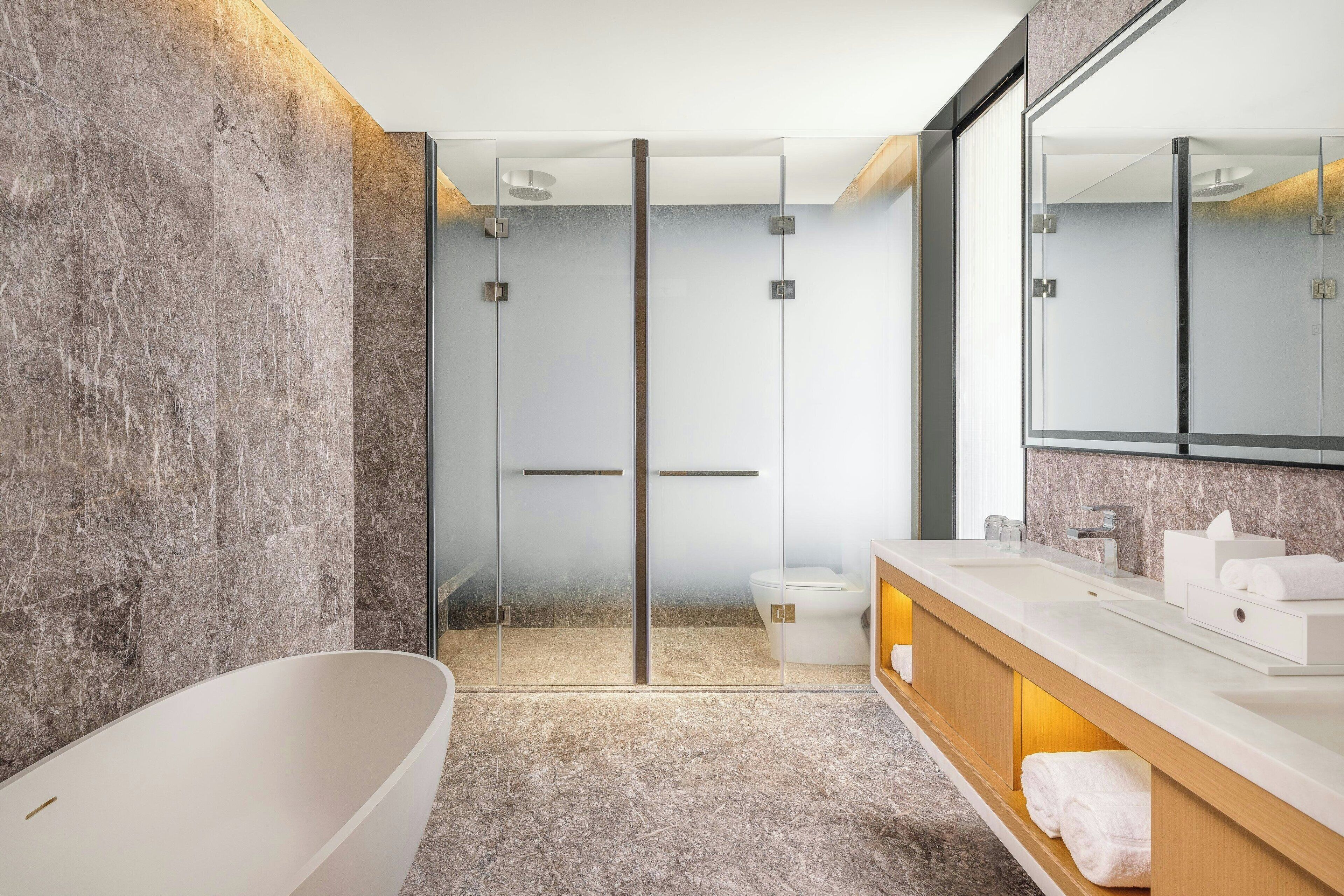 A modern bathroom with a freestanding bathtub, a glass shower enclosure, and a vanity with a mirror and towel rack.