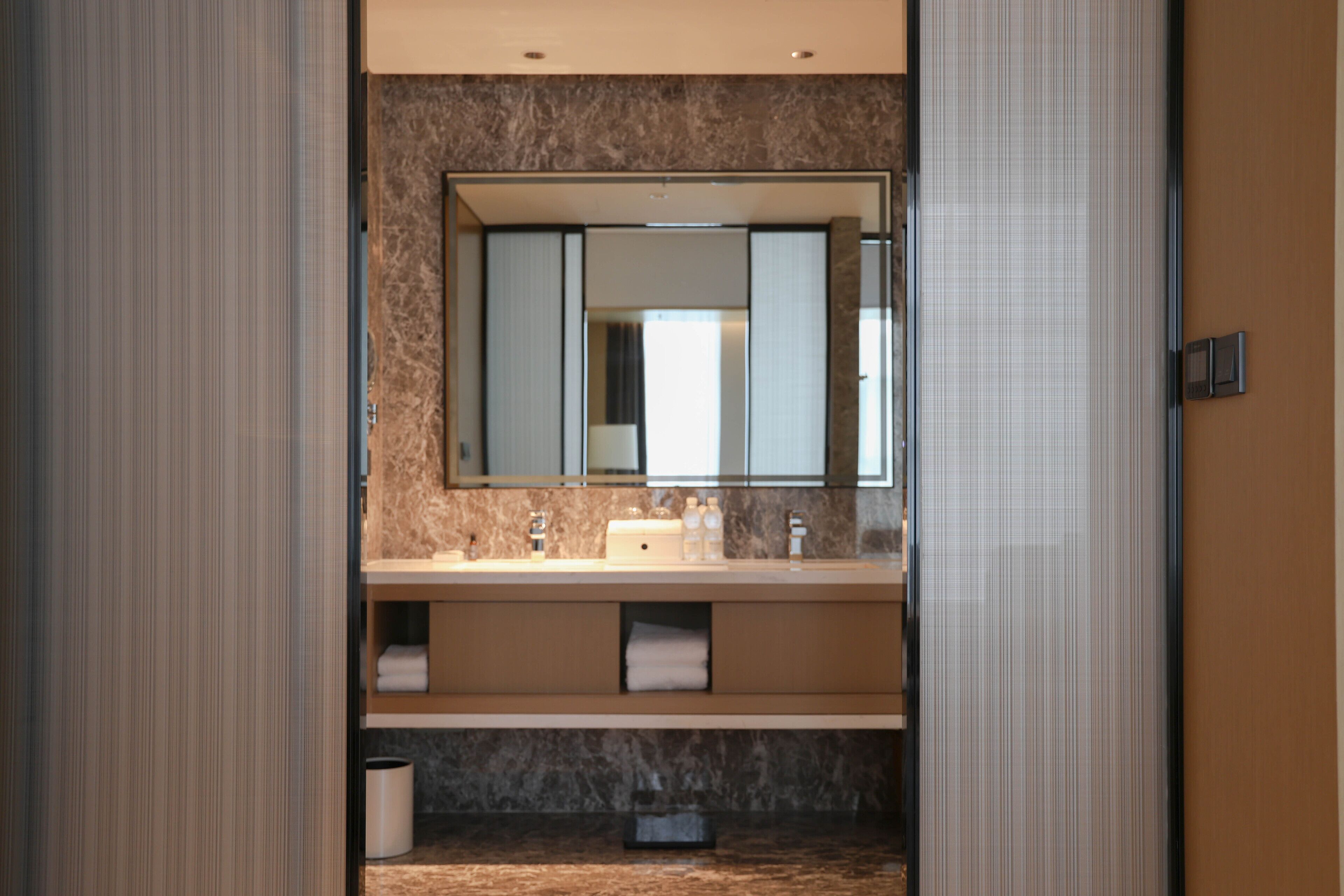 A modern bathroom with a large mirror, two sinks, and a marble countertop.