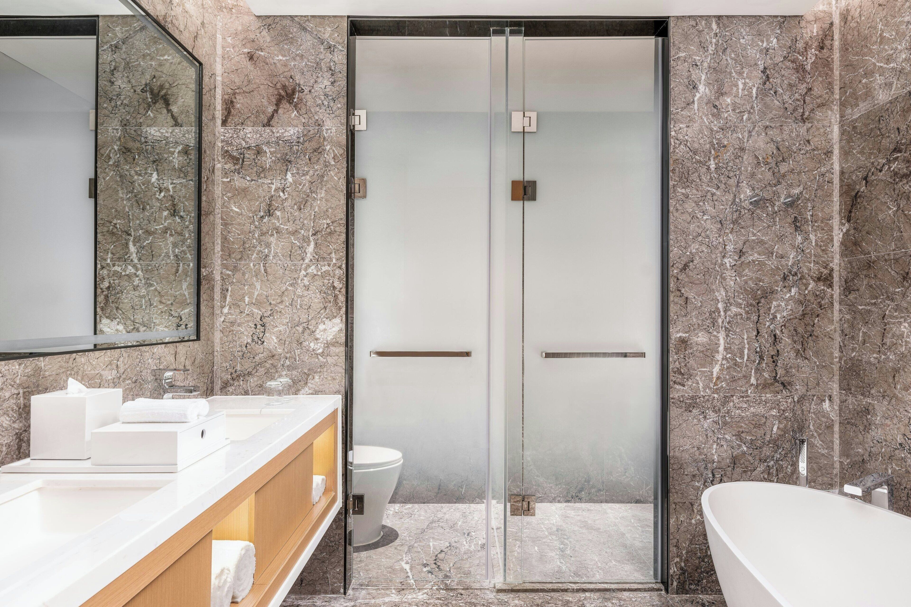 Un baño moderno con ducha envuelta en vidrio, un lavabo blanco y un espejo grande.