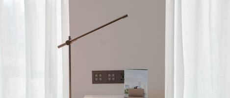 A modern desk with a lamp, a box, and a small display unit against a plain wall.