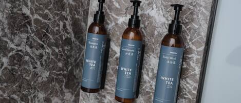 Tres botellas de gel de ducha y acondicionador Westin White Tea sobre una superficie de mármol.