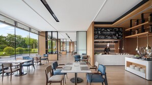 Un comedor moderno con mesas y sillas, una encimera de cocina y vistas al exterior.