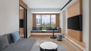 Una sala de estar moderna con un sofá, una mesa redonda y un televisor montado en la pared.