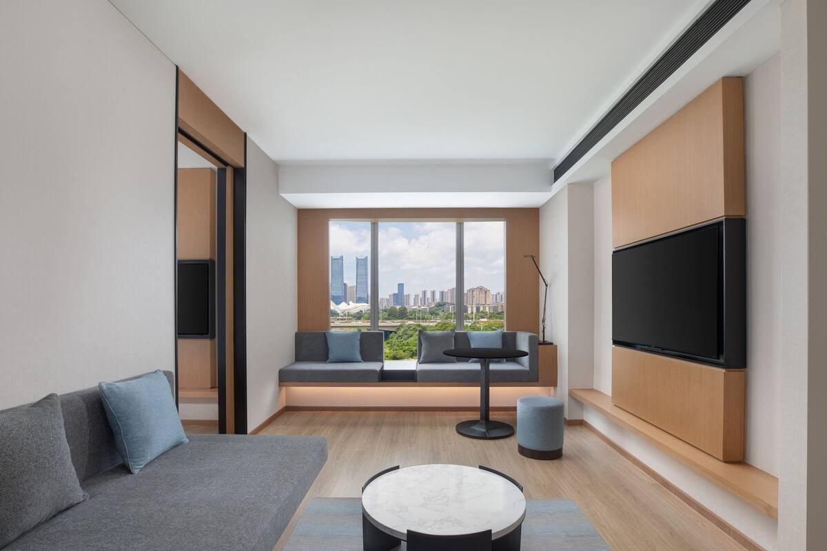 A modern living room with a sofa, a round table, and a TV mounted on the wall.