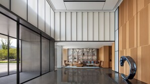 Un interior moderno con piso reflectante, un área de estar central con sofás y sillones, y una escultura grande a la derecha.