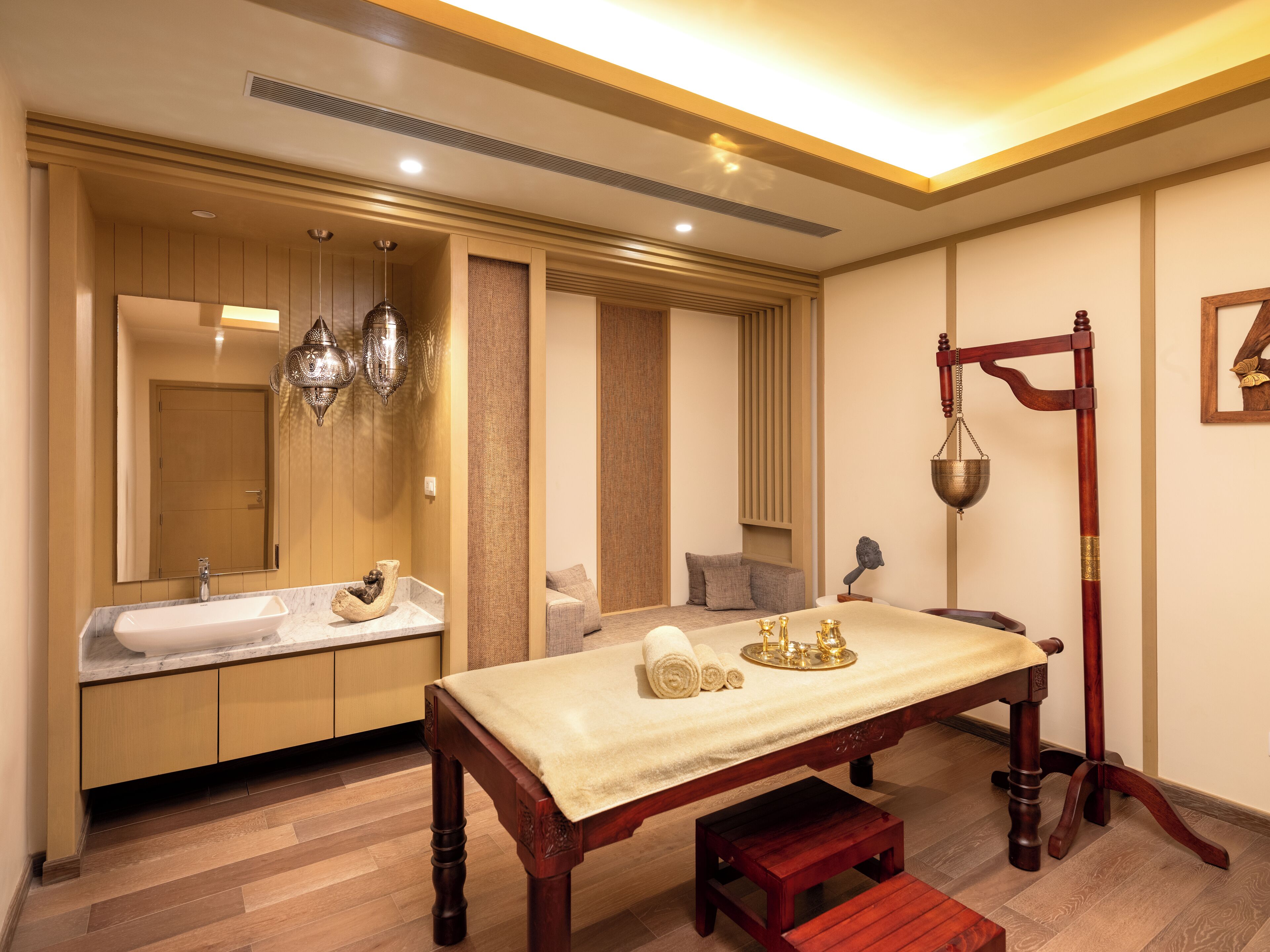 A modern bathroom with a large mirror, a sink, and a vanity. There is a wooden bench with a towel and a scale.