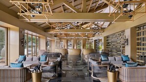 A spacious lobby with modern seating arrangements, a high ceiling with exposed beams, and a large window providing natural light. - Coorg Marriott Resort & Spa (Madikeri)