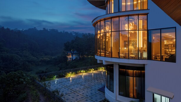 A modern building with large windows and a curved design, surrounded by a lush landscape. - Coorg Marriott Resort & Spa (Madikeri)