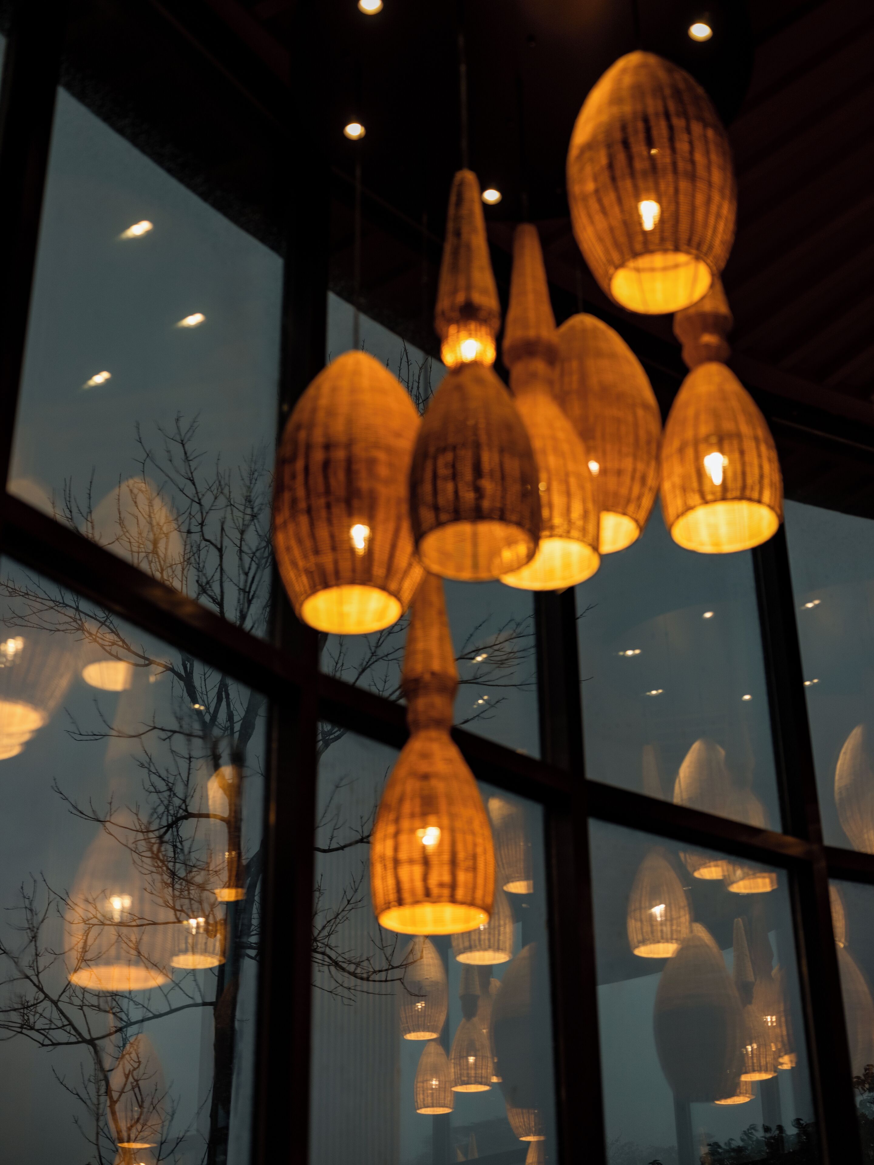 A modern interior with multiple hanging pendant lights and a large window with a view of bare trees.