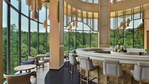 A modern bar area with high ceilings, large windows, and wicker furniture. - Coorg Marriott Resort & Spa (Madikeri)