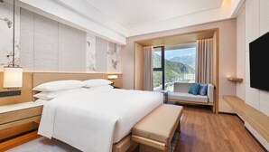 Una habitación de hotel moderna con una cama grande, un banco, un sofá y un televisor.
