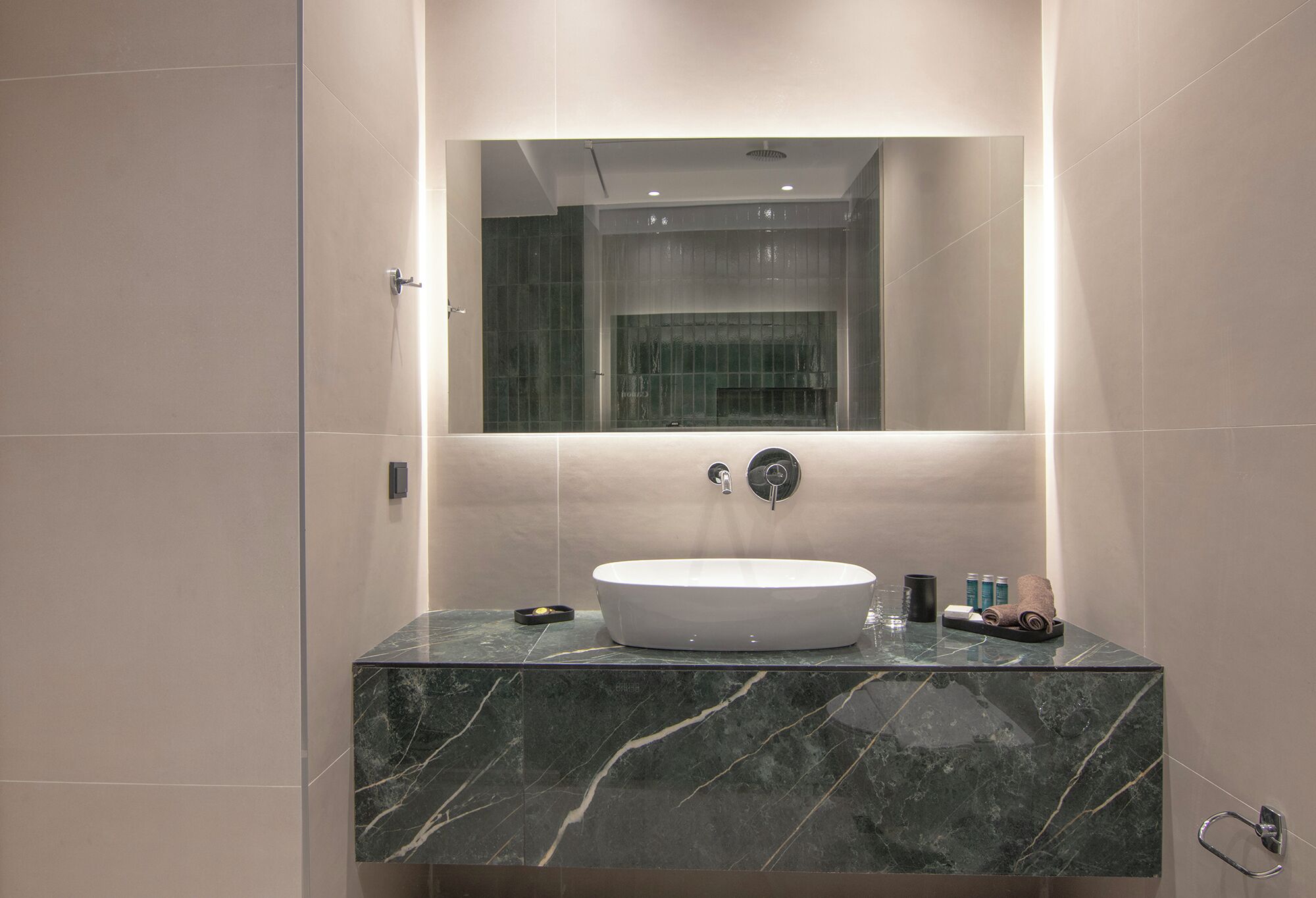 A modern bathroom with a large mirror, a round sink, and a marble countertop.
