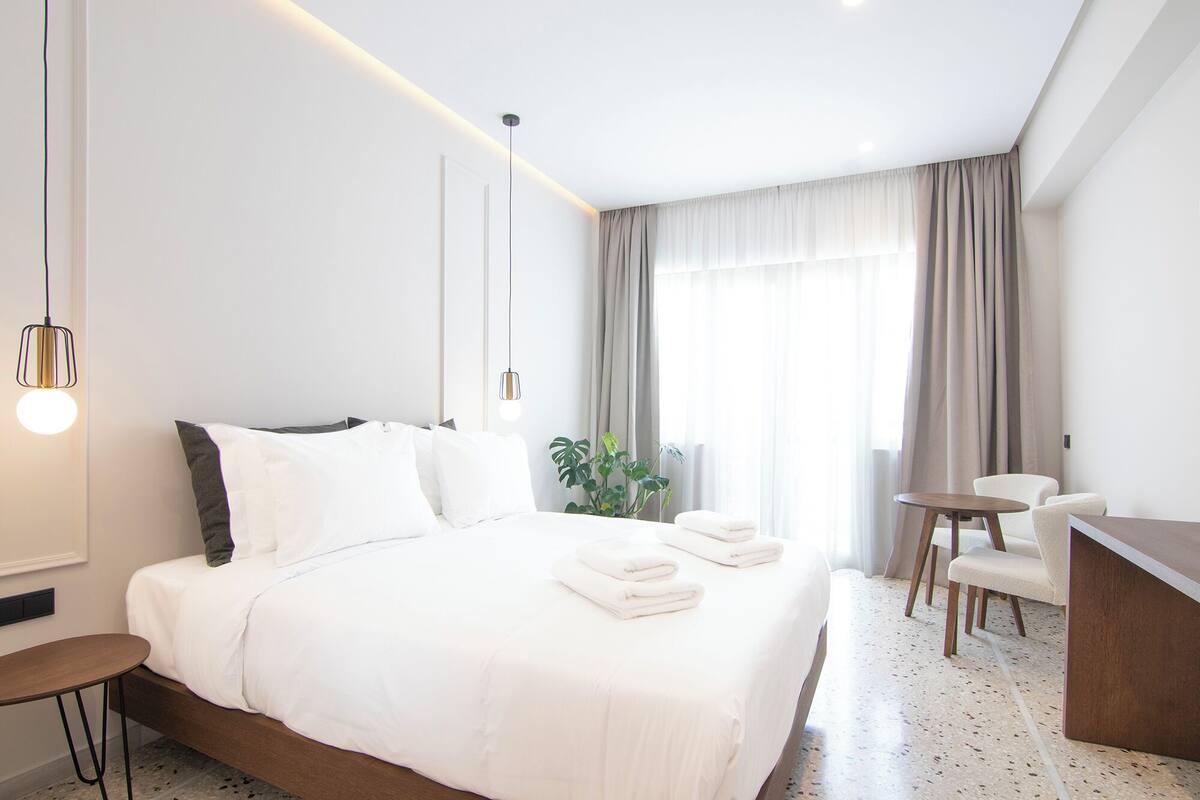 A modern hotel room with a neatly made bed, a desk, and a chair.