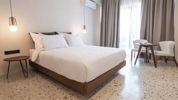 Una habitación de hotel moderna con una cama grande, una mesita pequeña, una silla y un escritorio.