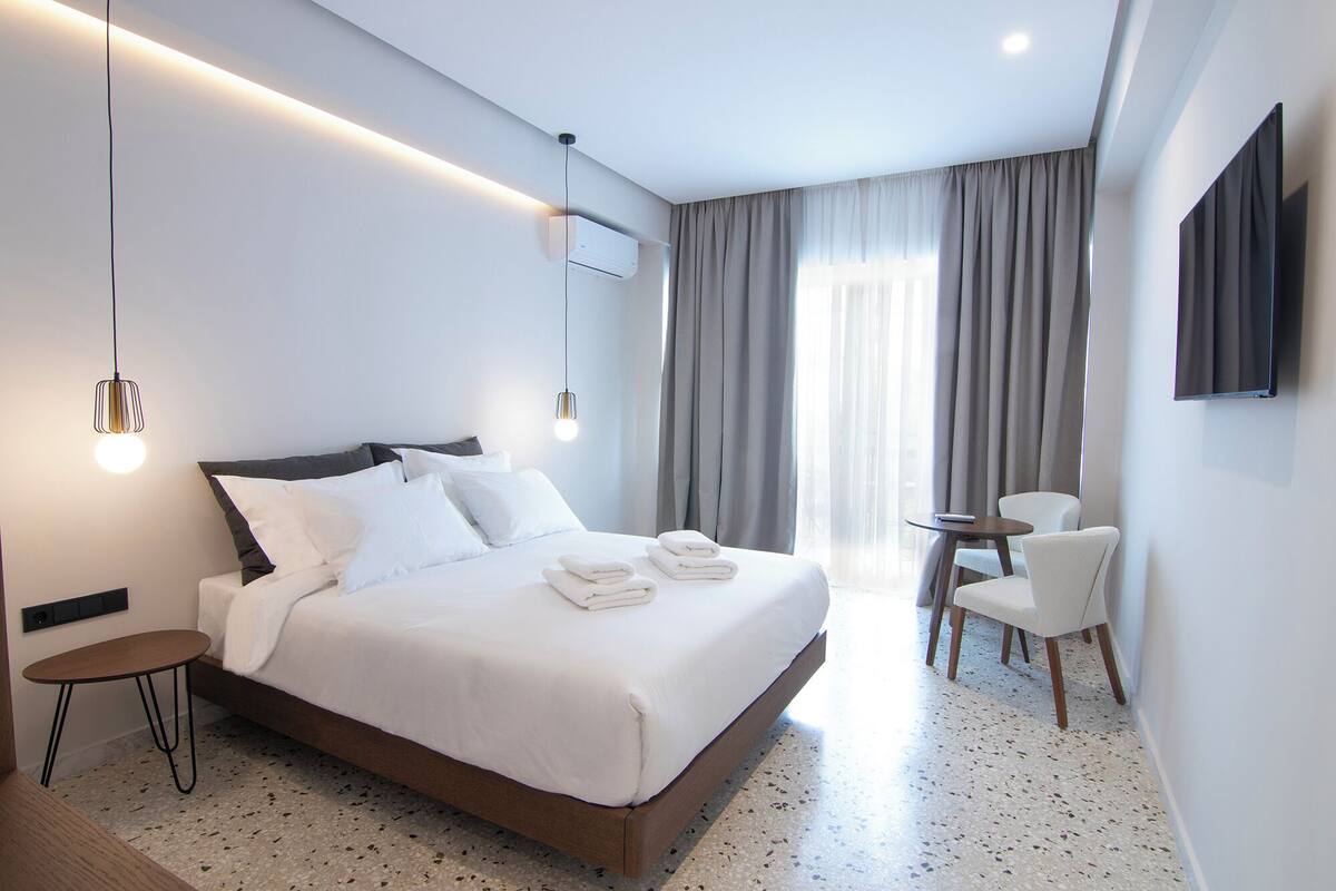 A modern hotel room with a large bed, bedside tables, a desk, and a chair.