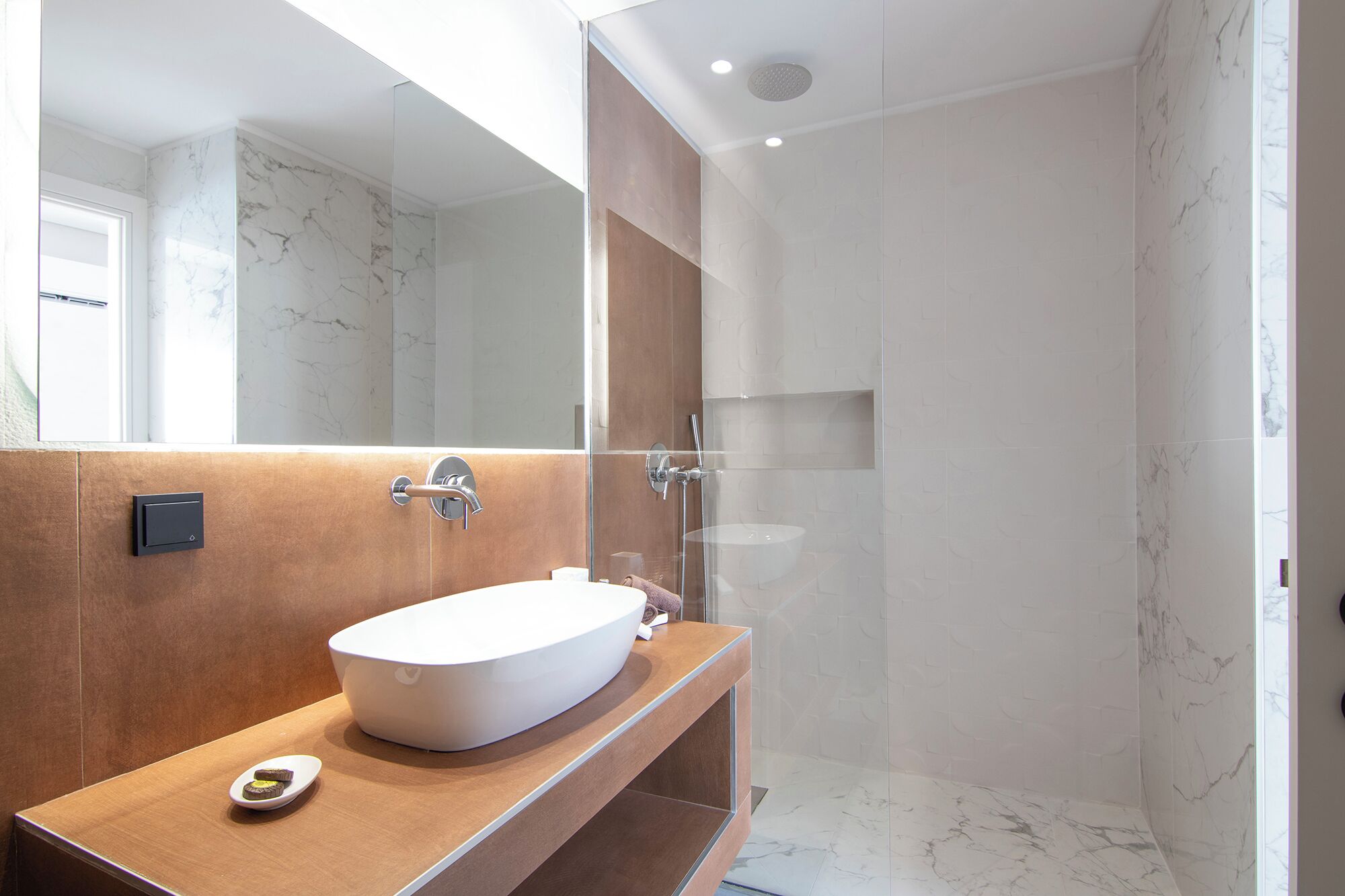 Une salle de bain moderne avec un grand lavabo ovale, un miroir et un espace douche.