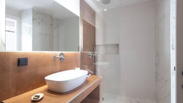 Une salle de bain moderne avec un grand lavabo ovale, un miroir et un espace douche.
