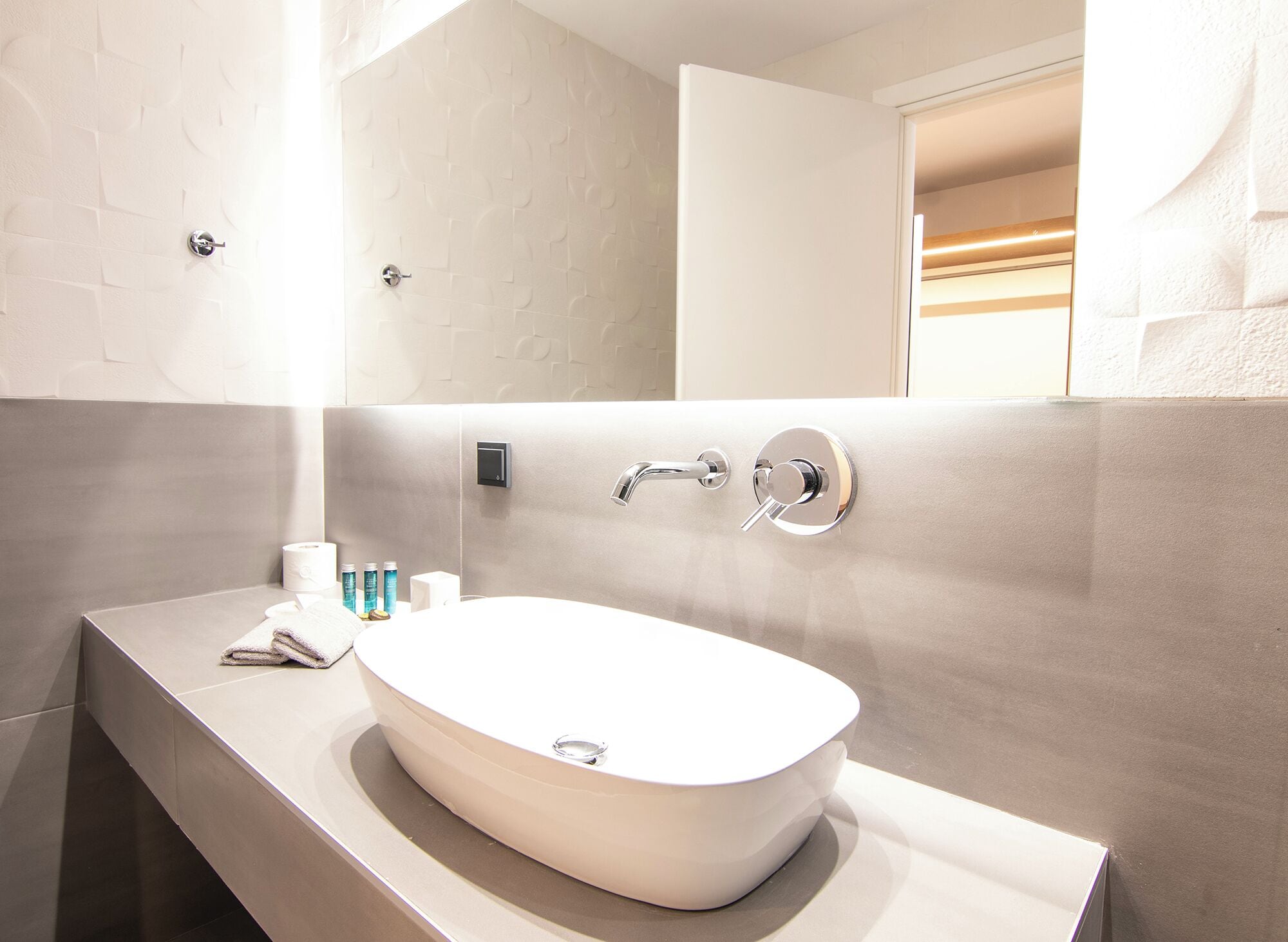 A bathroom with a white sink, a mirror, and a towel on the counter.