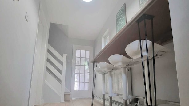 Un pasillo con piso de madera, una lámpara en el techo y una escalera que lleva a otra habitación.