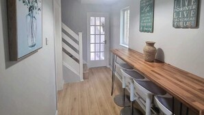 Una cocina moderna con encimera de madera, taburetes de bar y una escalera que sube a otra habitación.