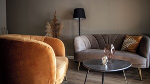 A living room with a sofa, a round coffee table, and a floor lamp. - Logement In De Peel (Griendtsveen)