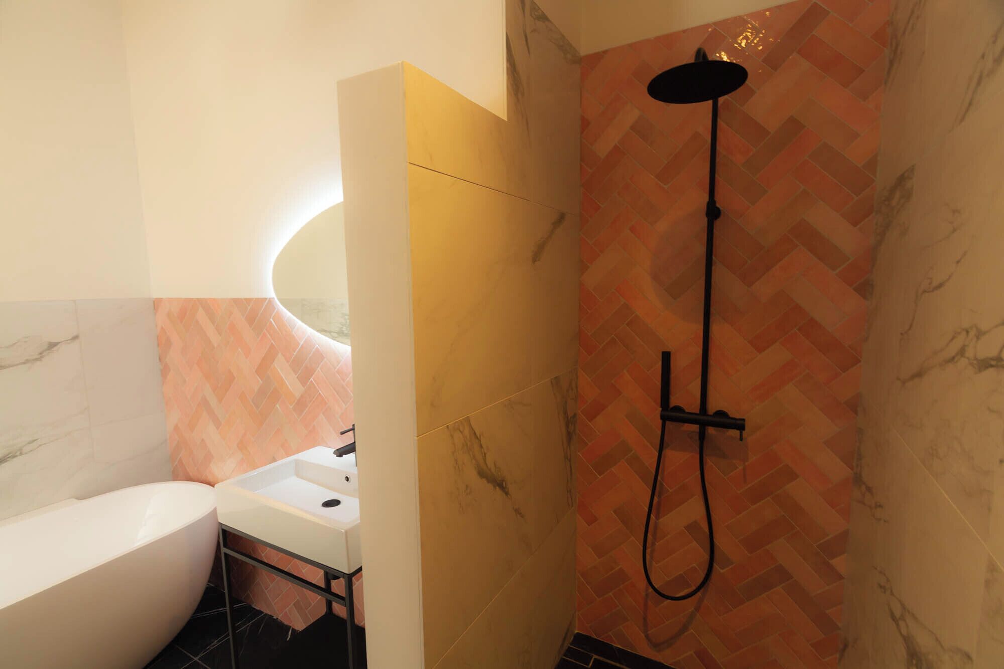 A bathroom with a white bathtub, a sink, and a shower with a herringbone-patterned wall.