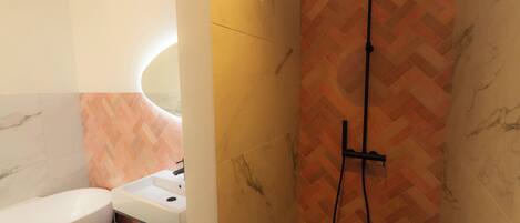 A bathroom with a white bathtub, a sink, and a shower with a herringbone-patterned wall.