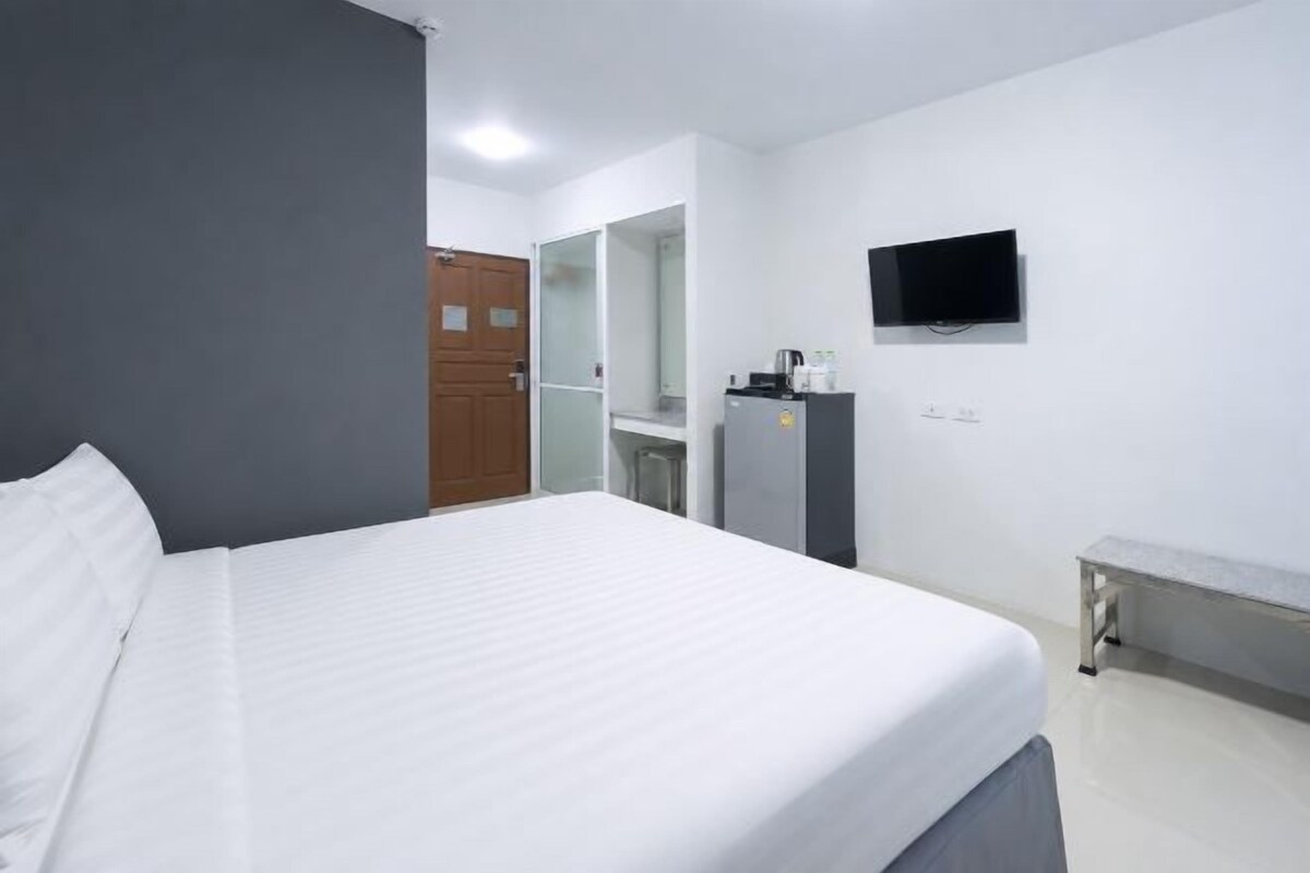 A hotel room with a bed, a desk, a mirror, a television, and a wardrobe.
