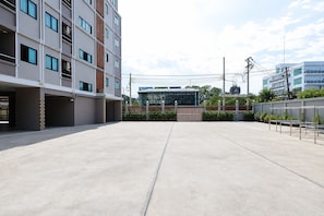 A modern building with multiple floors, a covered parking area, and a gated entrance.