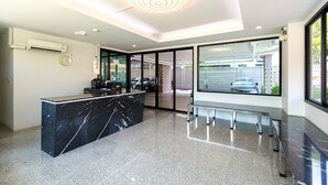 Ein moderner Empfangsbereich mit Marmorzauber, Glastüren zum Außenbereich und einer Decke mit runder Beleuchtung.