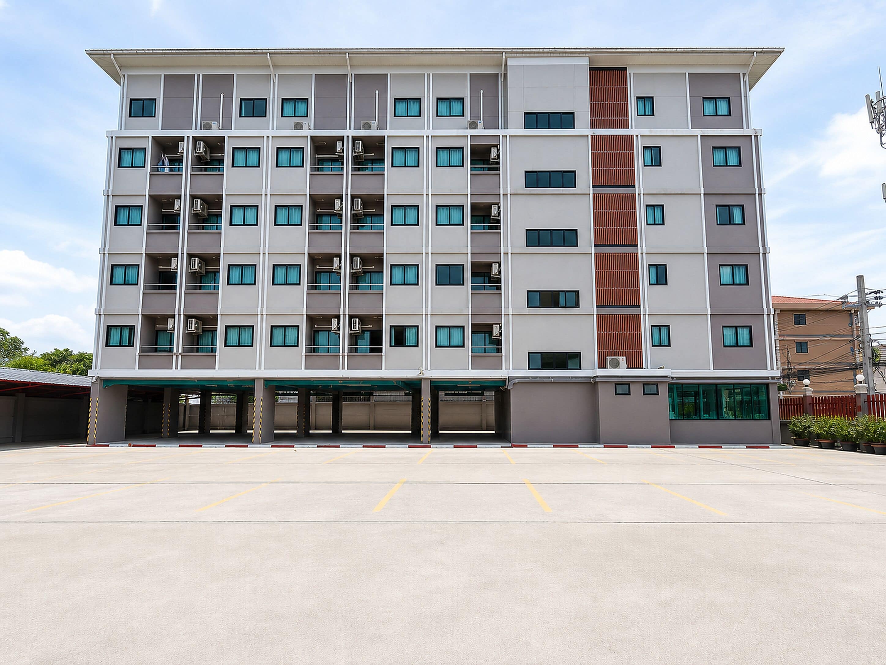 Un hôtel à plusieurs étages, doté d’une façade sobre, de nombreuses fenêtres et d’un espace de stationnement à l’avant.