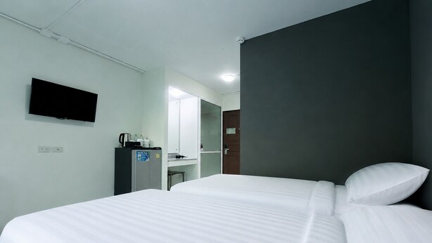 Ein Hotelzimmer mit Bett, Flachbildfernseher an der Wand, Kühlschrank, Kaffeemaschine und Spiegel.