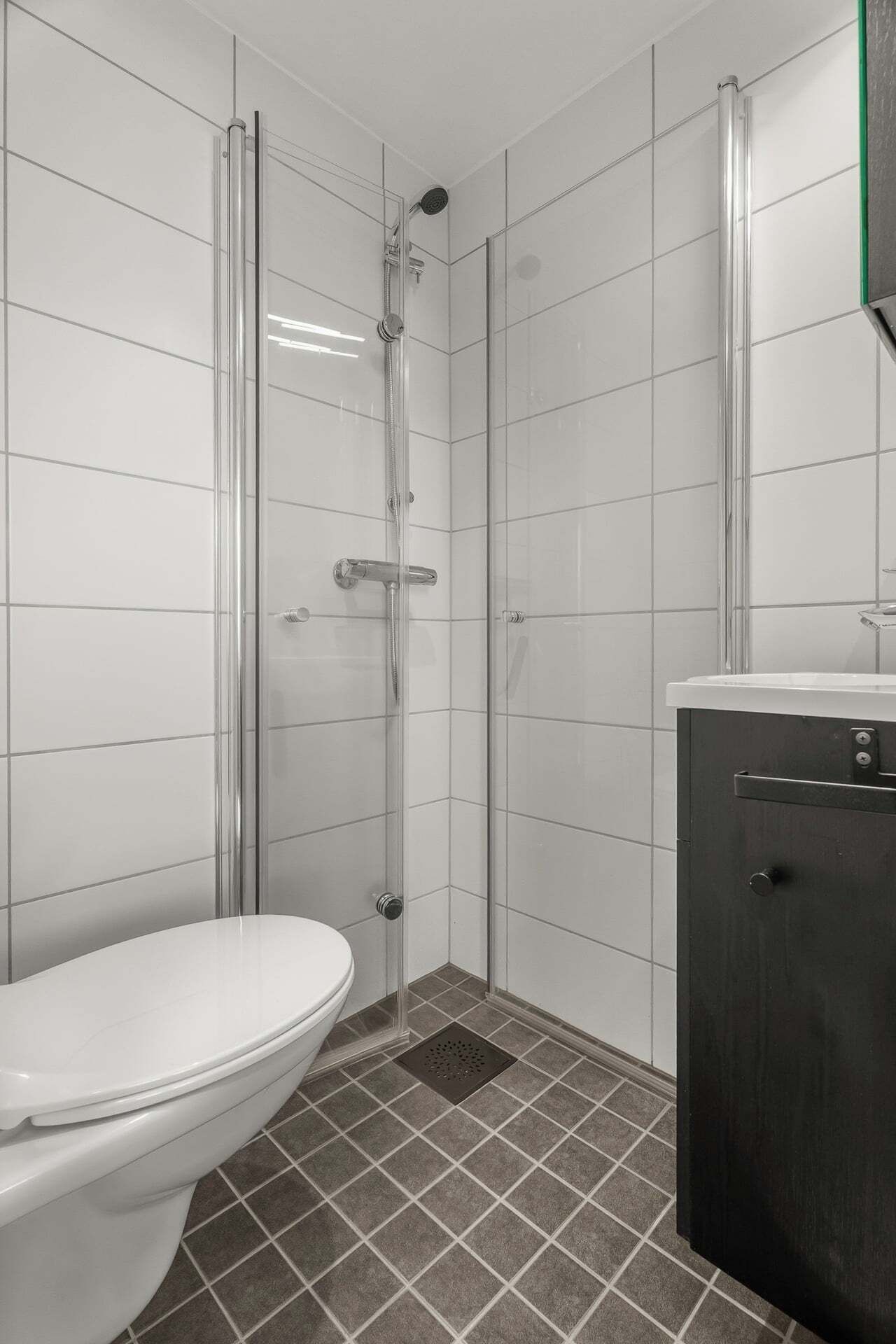 A bathroom with a toilet, a shower enclosure, and a sink.