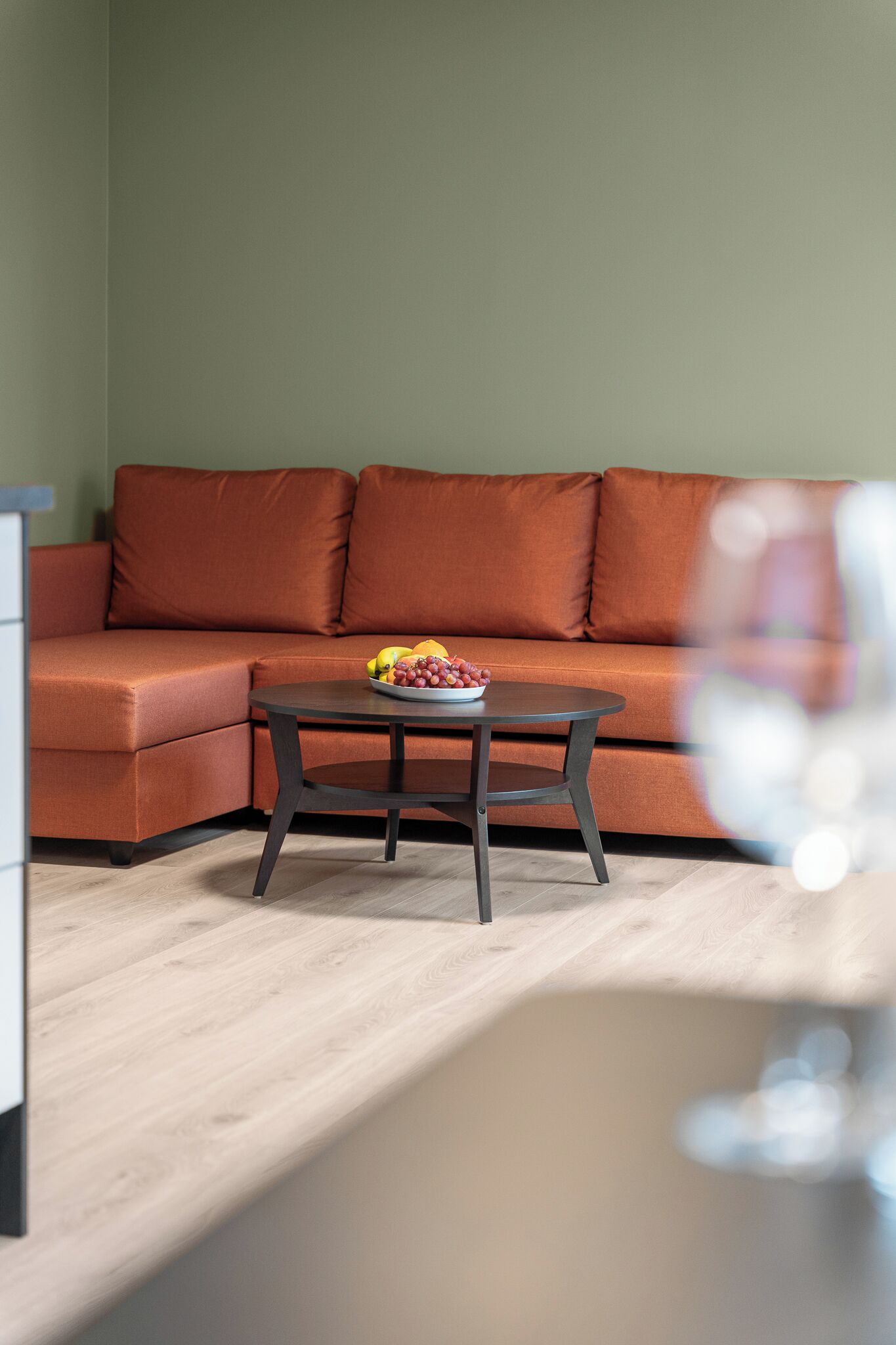 Un salón con un sofá, una mesa de centro con fruta y una copa de vino.