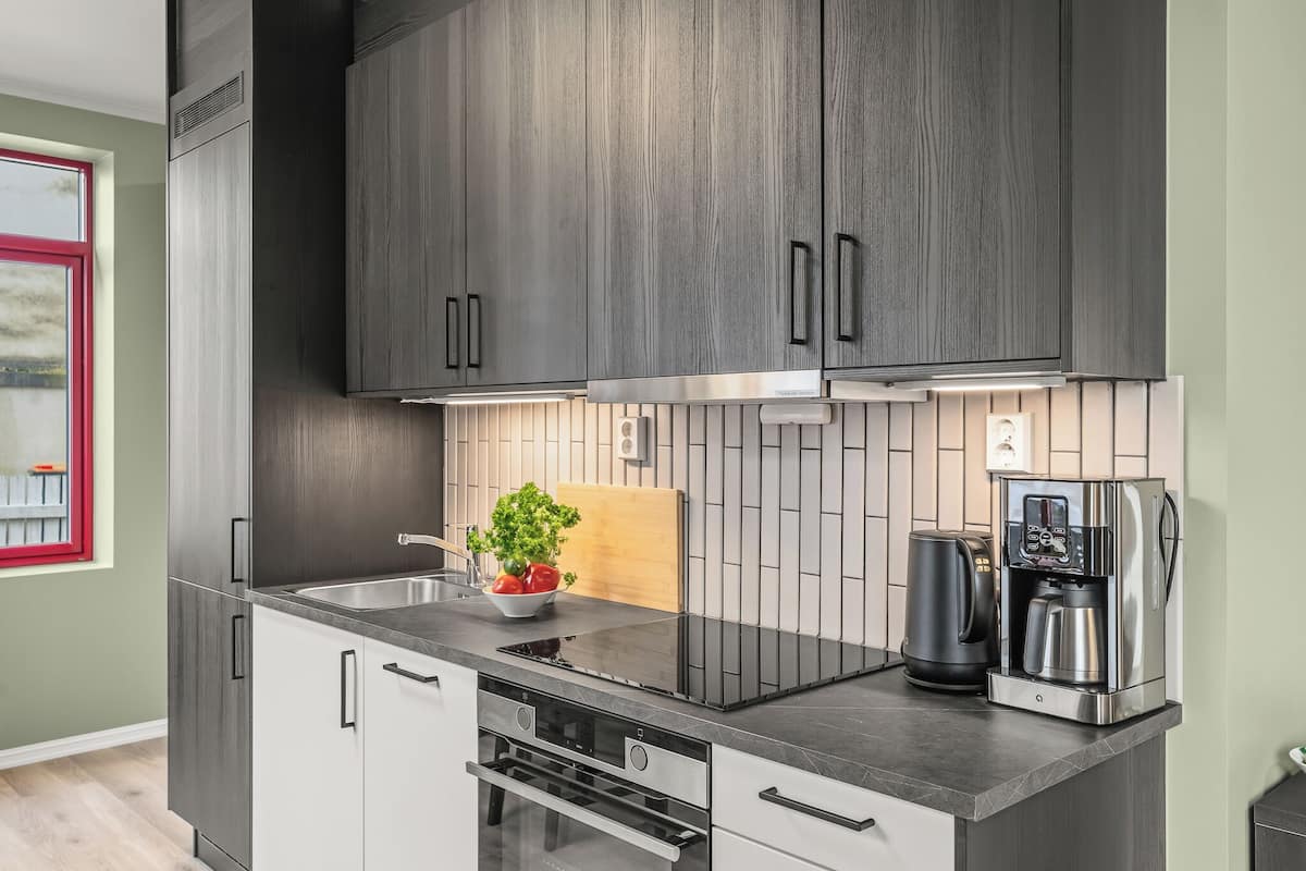 Eine moderne Küche mit dunklen Holzschränken, Edelstahlgeräten und einer schwarzen Arbeitsplatte.
