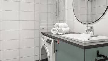 A modern bathroom with a washing machine, a sink, and a mirror.
