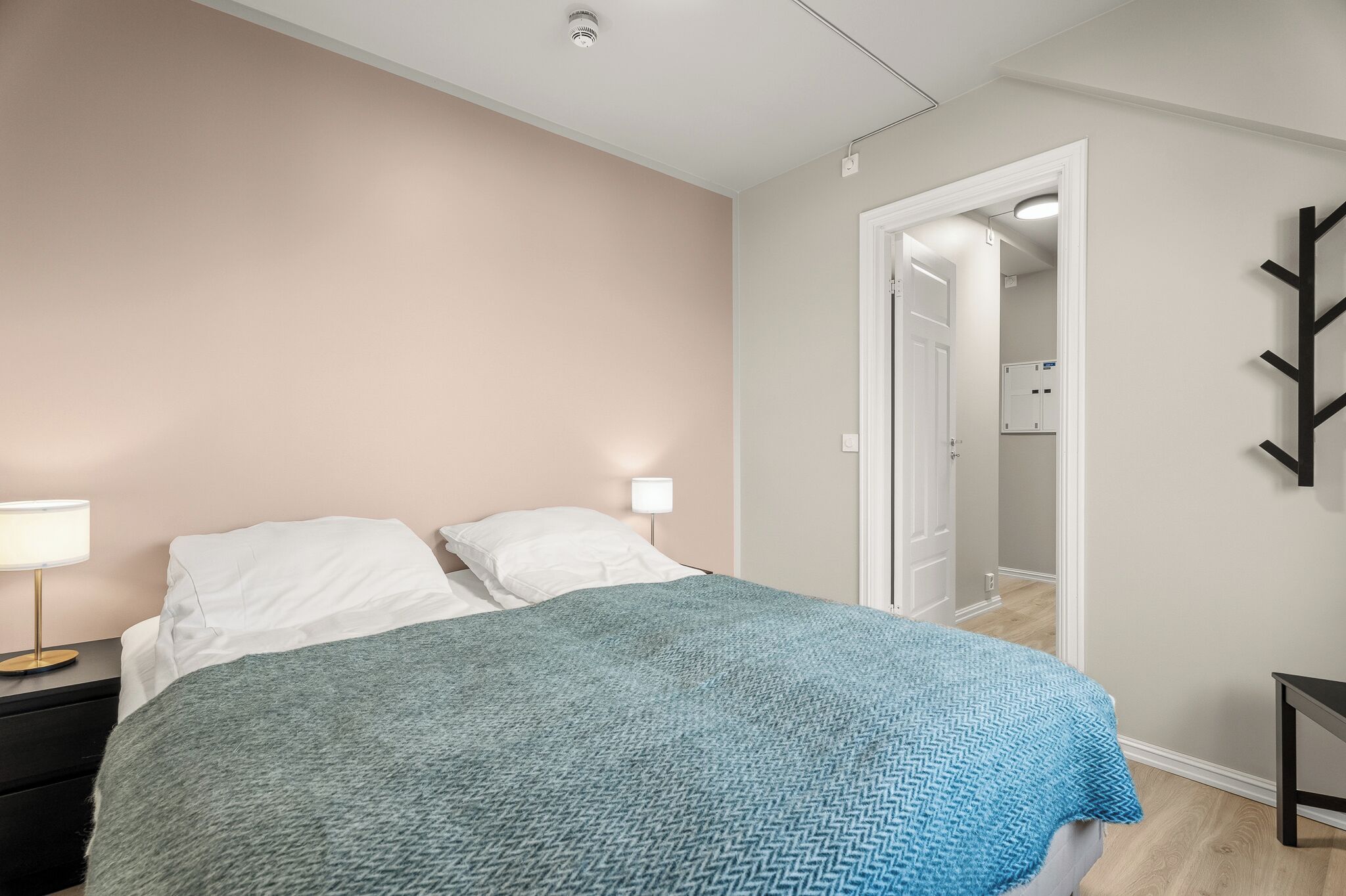 Un dormitorio con cama, lámparas de noche, armario y espejo.