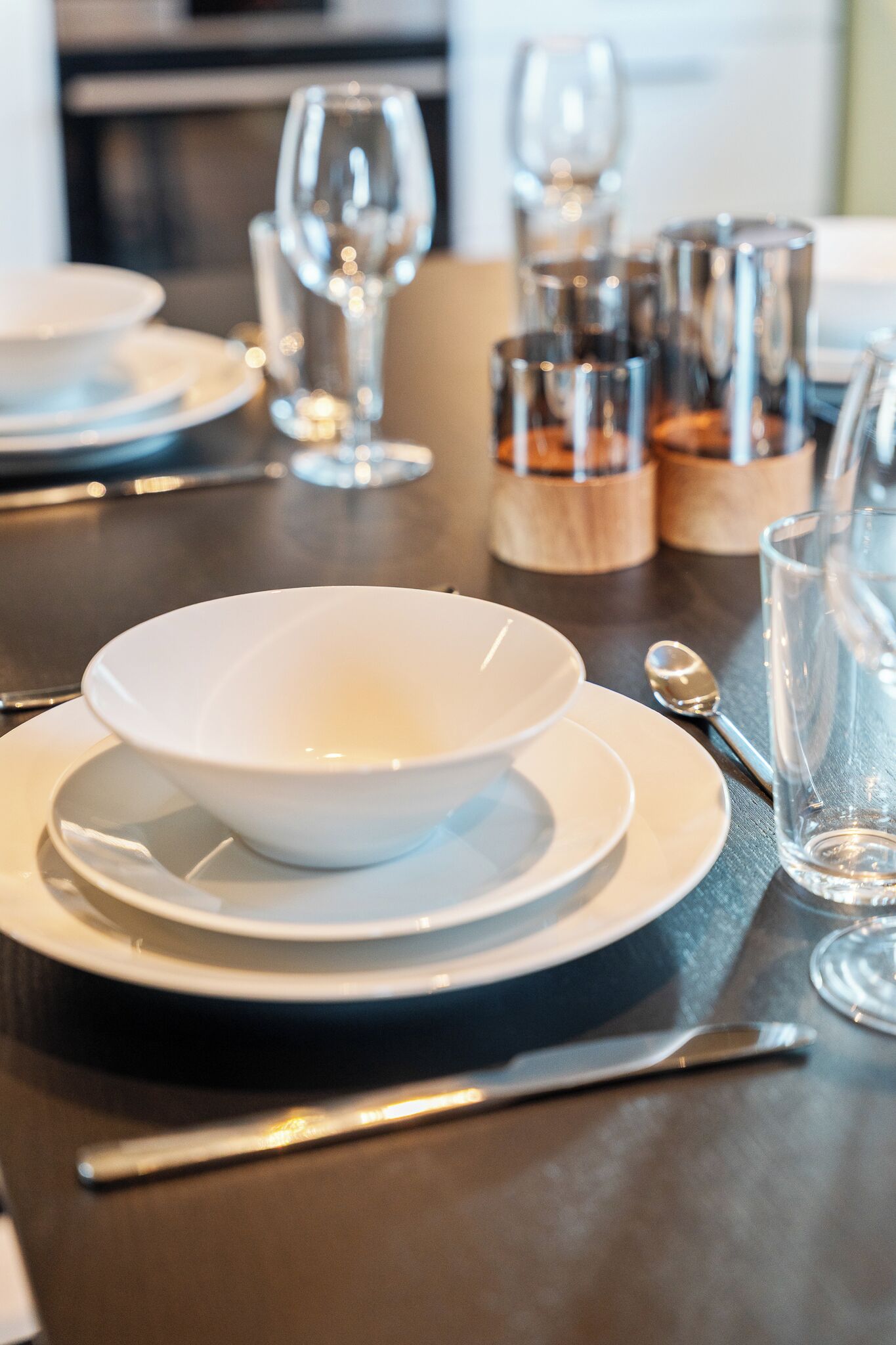 A dining table set with white plates, bowls, and cutlery.