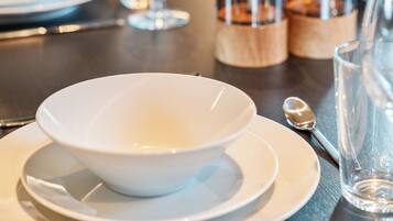 A dining table set with white plates, bowls, and cutlery.