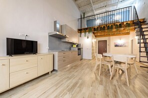 Une cuisine moderne équipée d’un téléviseur, de meubles en bois et d’un coin repas avec une table et des chaises.